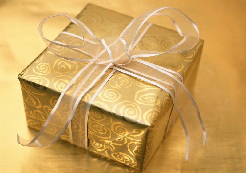 A gold gift box with a swirl pattern, tied with a white ribbon bow